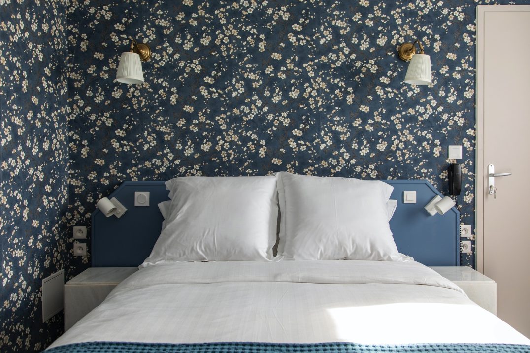 Lit devant un mur au papier-peint fleuri dans la chambre classique de l'hôtel Lit devant un mur au papier-peint fleuri dans la chambre classique de l'hôtel